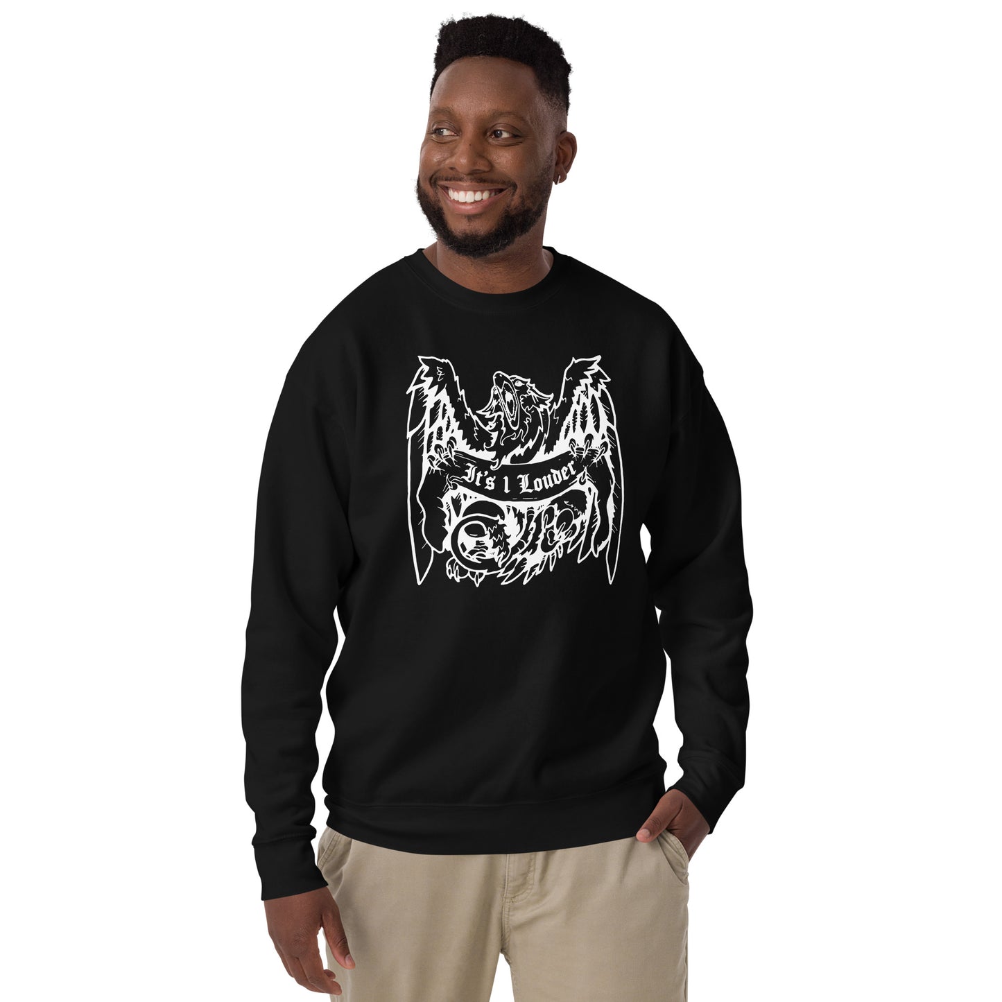 Black man smiling and looking off to his right side is wearing a black long sleeve shirt with an image of a griffin which is a half-eagle half lion beast. The griffin is holding a banner. The words "It's 1 Louder" is written on the banner. The griffin has its wings spread wide and beak fully open. The entire graphic is in white and it printed right in the centre of the shirt.