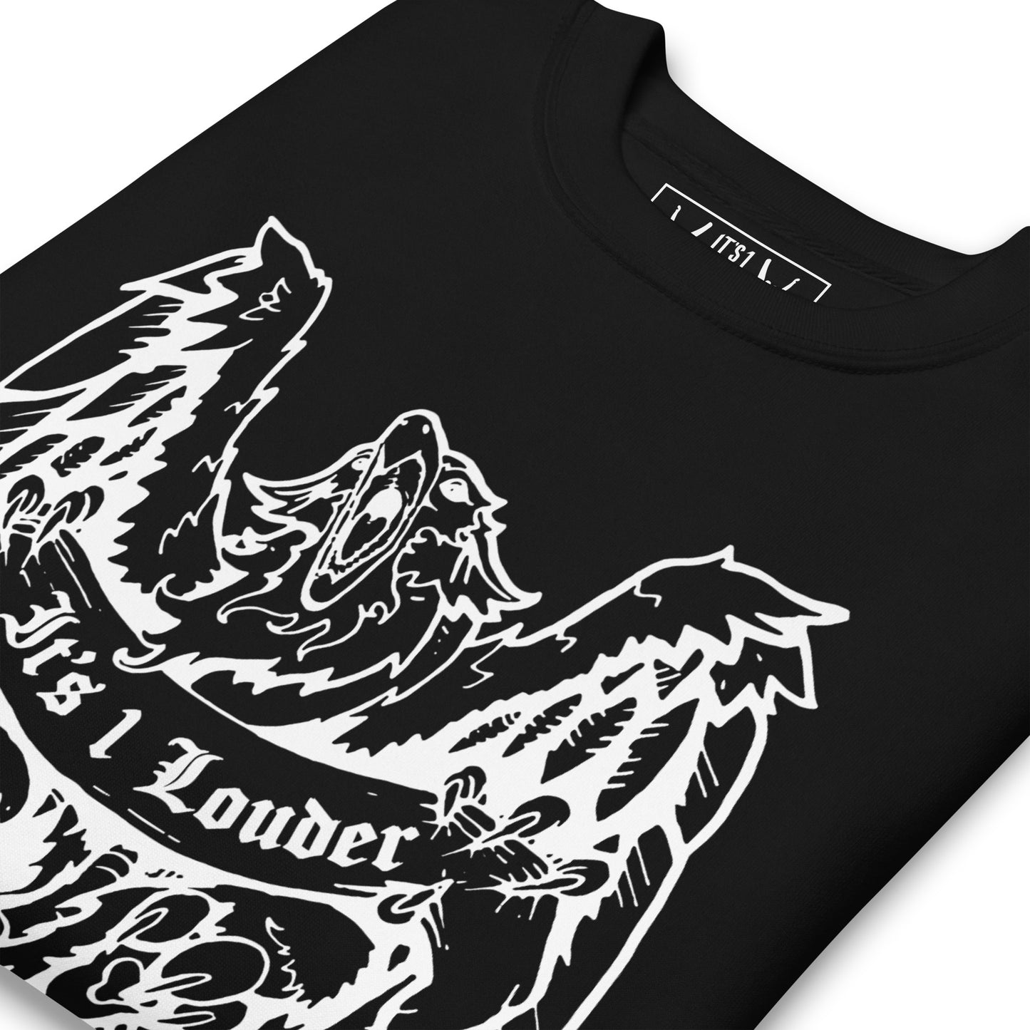Black sweater with an image of a griffin which is a half-eagle half lion beast. The griffin is holding a banner. The words "It's 1 Louder" is written on the banner. The griffin has its wings spread wide and beak fully open. The entire graphic is in white. This sweater definitely gives off a punk look or rock style look. Image is a close up of the front of the tee where you see the griffin design and part of the inside label. The sweater is folded.