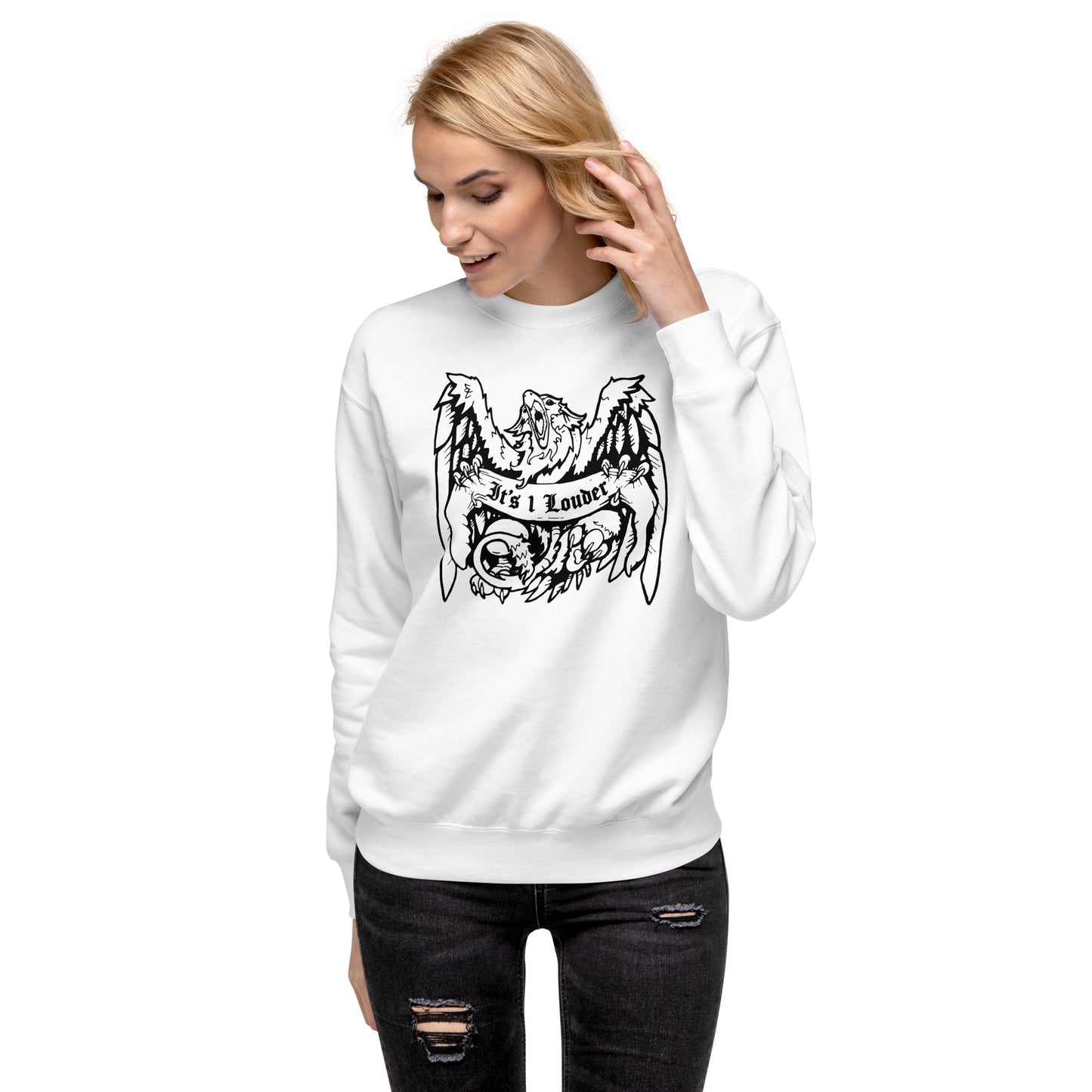 A front view of a caucasian blonde haired woman wearing a white sweater with an image of a griffin which is a half-eagle half lion beast holding a banner with it's claws. The griffin has its wings spread wide and its beak is fully open. The entire graphic is in black. The words IT'S 1 LOUDER is written on the banner.
