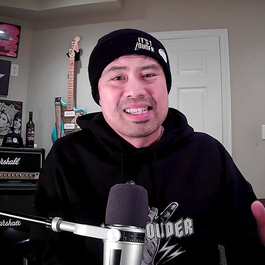 PJ Pat smiling on the It's 1 Louder podcast wearing the black Volume Knob Rockstar Beanie with It's 1 Louder text and volume knob