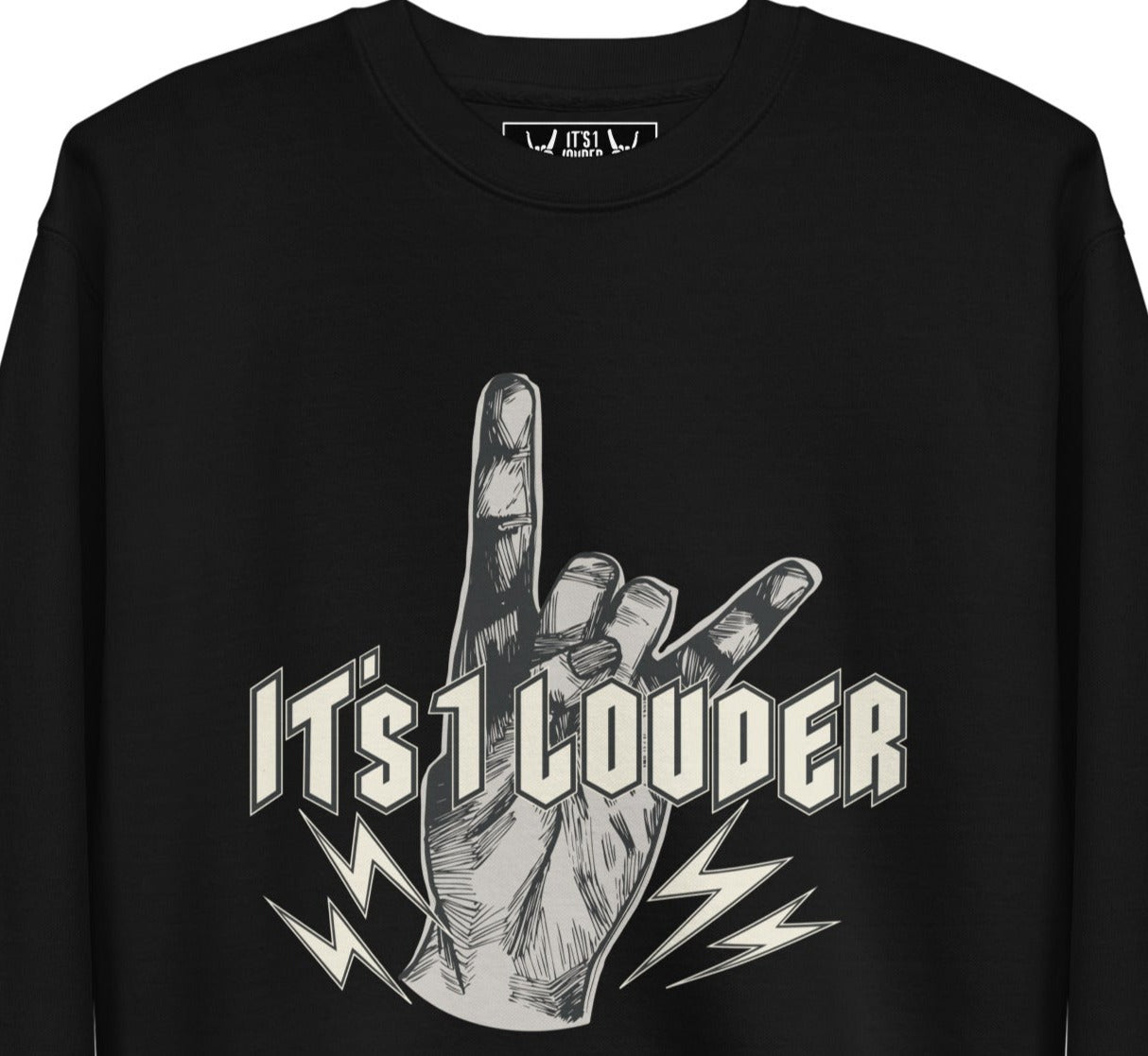 Black long sleeve shirt/ sweater with a graphic of a hand doing the devil horns symbol for rock and roll. The words IT'S 1 LOUDER is written across the hand in a beige colour. The hand is of light grey colour. 4 small bolts of lightning are at the bottom of the palm and below the words "It's 1 Louder". Also shown, is the inside label of the T-shirt that shows two hands doing the rock symbol. In between the 2 hands is written the words: It's 1 Louder.