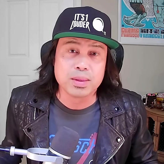PJ Pat, host of the It's 1 Louder rock podcast, wearing the black Volume Knob Rockstar Cap with the green underbrim and the volume knob turned to 11